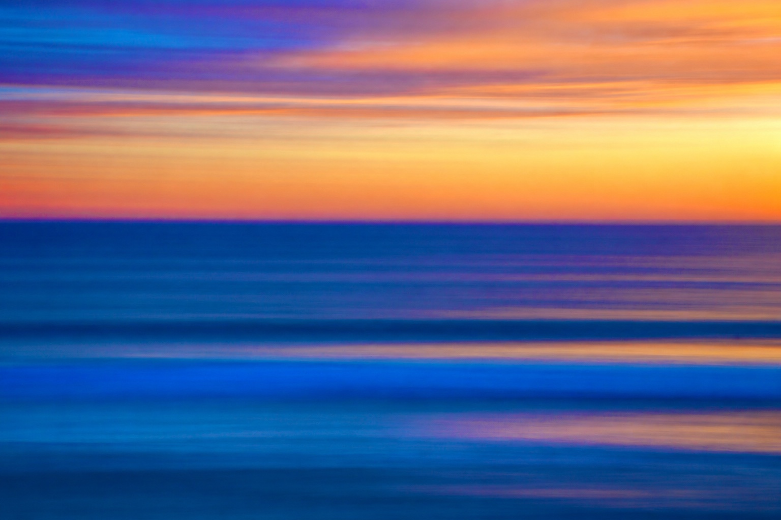 Deep blue ocean abstraction beneath bands of orange and violet light