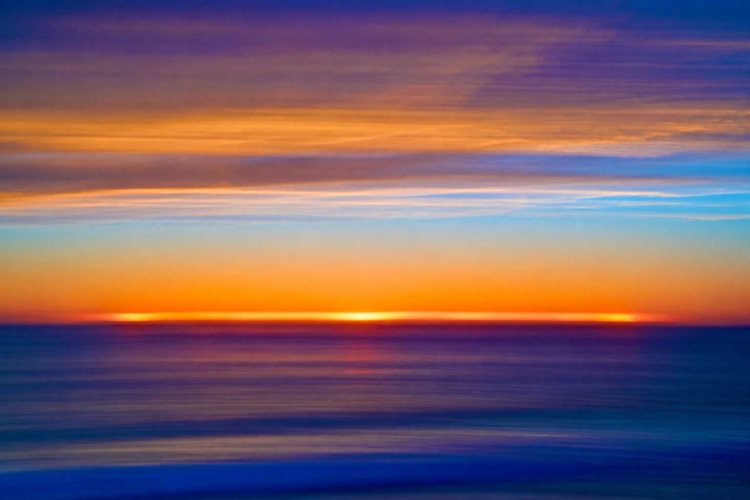 Abstract sunset with a luminous orange horizon beneath layered clouds